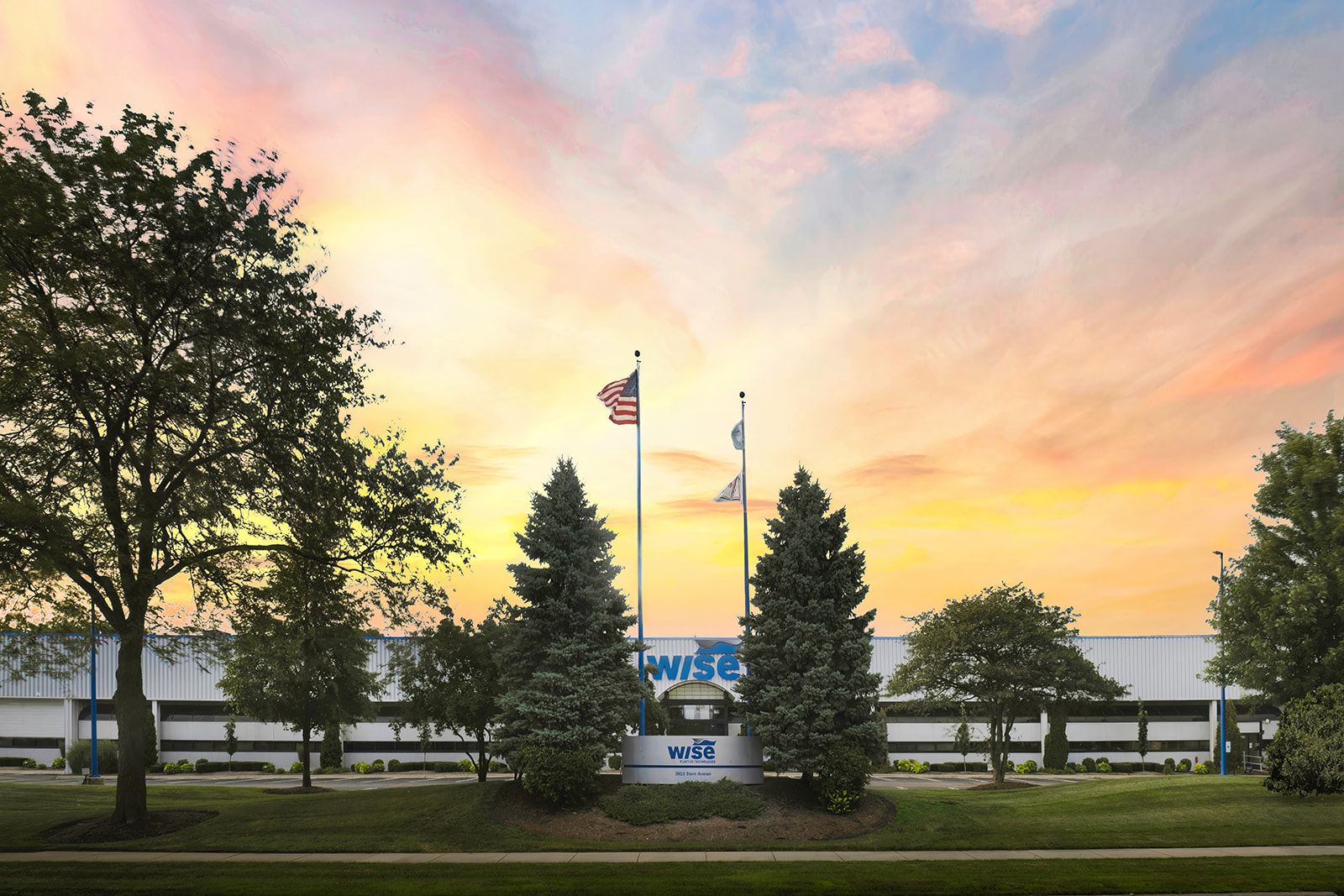 Sunset over the Wise Plastics St. Charles headquarters with the American flag and monument sign