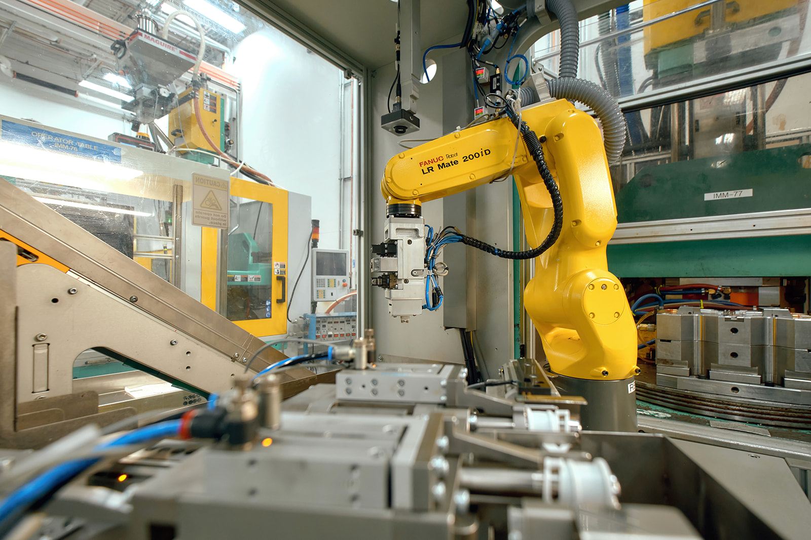 FANUC six-axis robot with end-of-arm tooling inside an automated molding cell at Wise Plastics