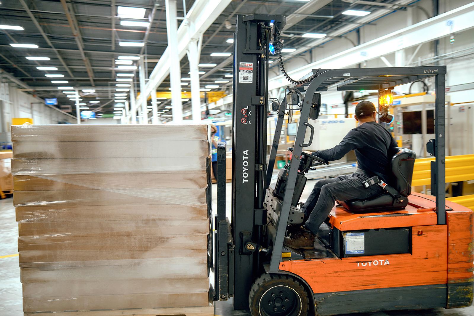 Forklift operator moving a stretch-wrapped pallet of finished goods through the Wise Plastics warehouse