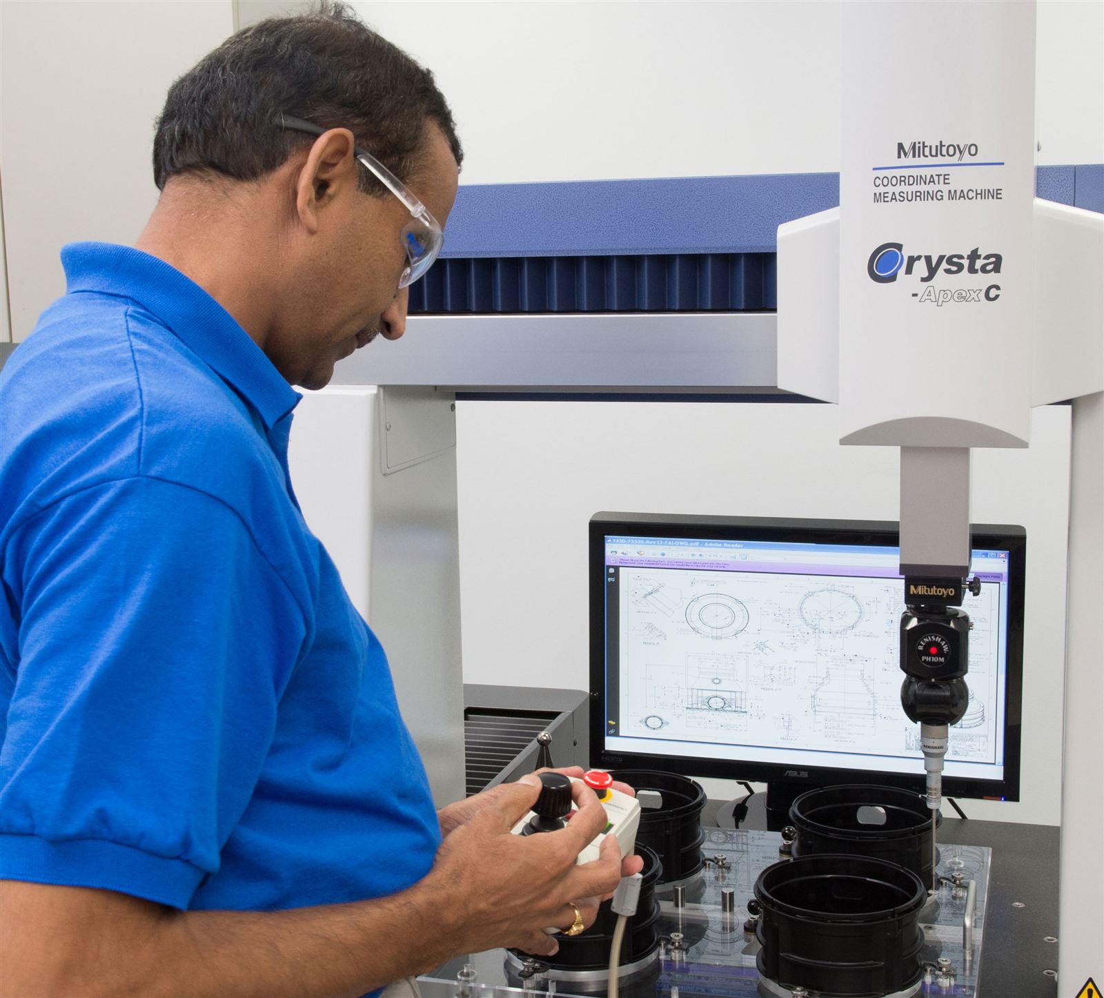 Wise Plastics quality technician operating a Mitutoyo Crysta-Apex coordinate measuring machine with the part drawing on screen